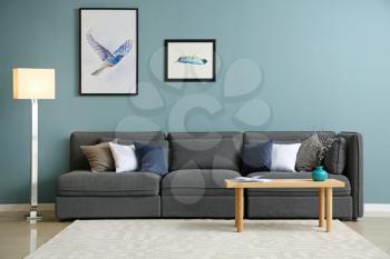 Comfortable sofa and table near color wall�