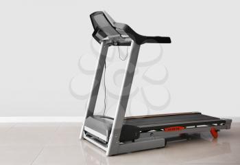 Modern treadmill near light wall�