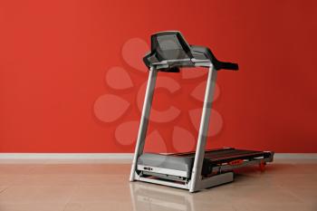 Modern treadmill near color wall�