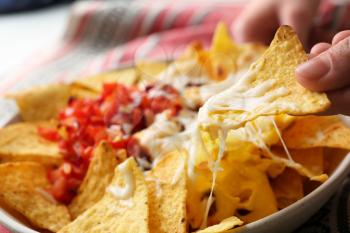 Woman eating tasty nachos with cheese, closeup�