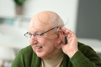 Senior man with hearing aid at home�