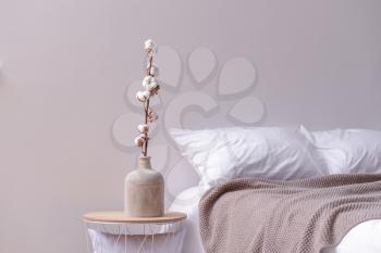 Vase with cotton flowers on table in bedroom�