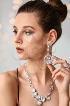 Young woman with beautiful jewelry on light background�