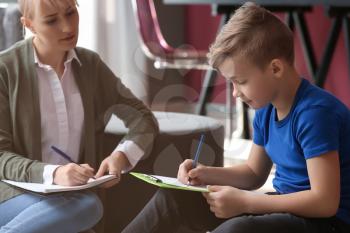 Female psychologist working with little boy in office�