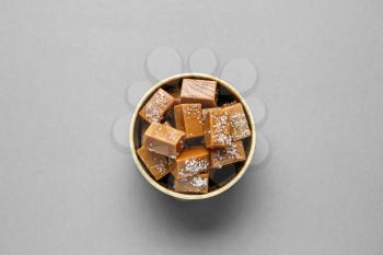 Bowl with tasty salted candies on grey background�