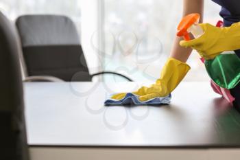 Female janitor cleaning table in office�