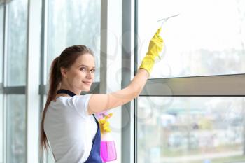 Female janitor cleaning window in office�