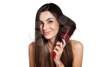 Beautiful young woman brushing her healthy long hair on white background�