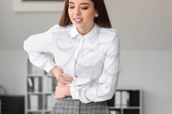 Young woman suffering from abdominal pain in office�