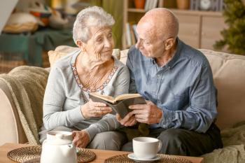 Portrait of senior couple reading book at home�