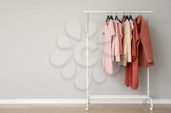 Rack with stylish clothes near grey wall�