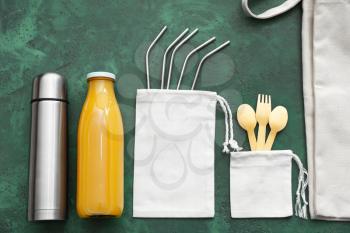 Bags with cutlery, straws, bottle of juice and thermos on color background. Zero waste concept�