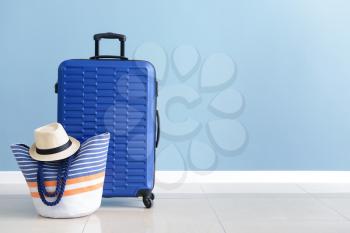 Packed suitcase and beach bag near color wall�