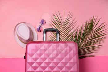 Suitcase, tropical leaves, sunglasses and hat on color background. Travel concept�