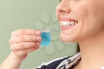 Woman with oral rinse on color background, closeup. Dental hygiene concept�