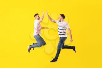 Jumping young men on color background�
