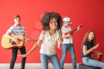 Teenage musicians playing against color wall�