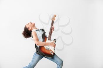 African-American girl playing guitar against light background�