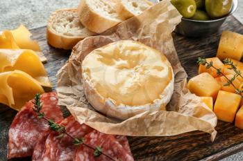 Melted cheese with different snacks on wooden board�