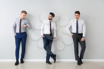 Fashionable young men near grey wall�