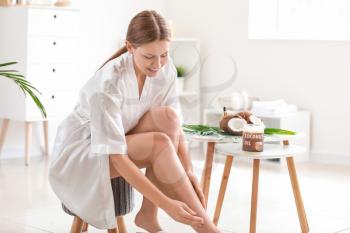 Beautiful young woman applying coconut oil at home�