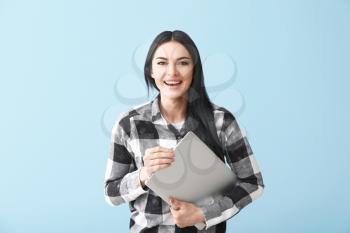 Happy female programmer with laptop on color background�