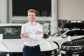 Salesman in modern car showroom�