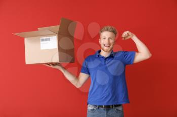 Young man with open cardboard box on color background�