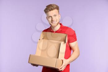 Young man with empty cardboard box on color background�