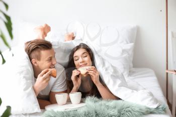 Cute young couple having breakfast in bed�