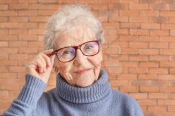 Portrait of senior woman on brick background�