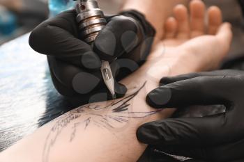 Professional artist making tattoo in salon, closeup�