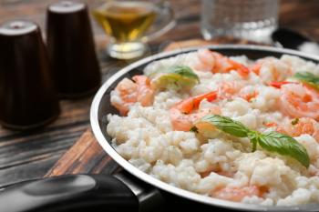 Frying pan with tasty risotto on table, closeup�