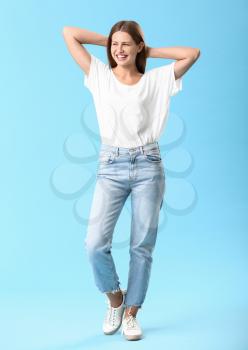 Stylish young woman in jeans on color background�