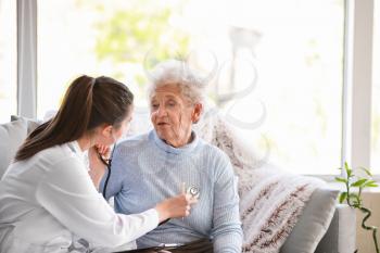 Doctor examining senior woman in nursing home 