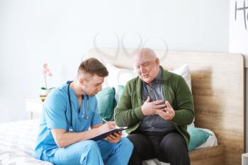 Medical worker with senior man in nursing home 