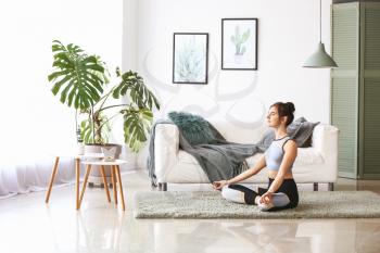 Young woman practicing yoga at home�