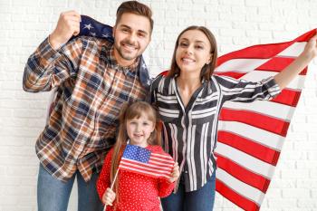 Happy young family with national flags of USA near white brick wall�