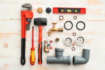 Set of plumbing tools on white wooden background�