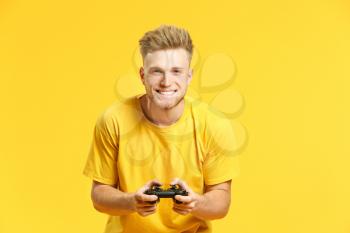 Portrait of handsome young man playing video games on color background�