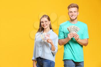 Happy couple with money on color background�