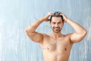 Handsome man washing hair on grey background�