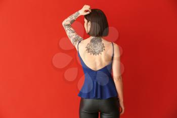 Beautiful tattooed woman on color background�
