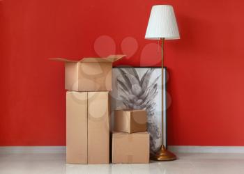 Cardboard boxes with belongings prepared for moving into new house near color wall�