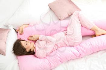 Young pregnant woman sleeping on maternity pillow at home�