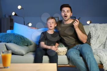 Father with son watching scary movie in evening�