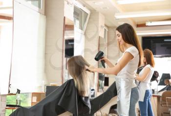 Female hairdresser working with client in salon�