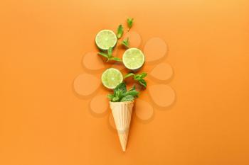 Waffle cone with fresh lime and mint leaves on color background�