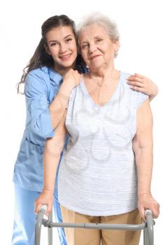 Young caregiver with senior woman on white background 
