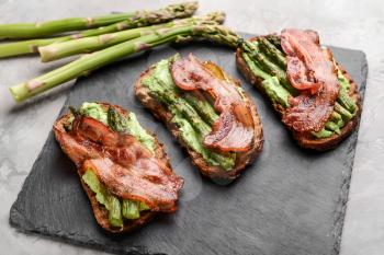 Tasty toasts with bacon on slate plate�